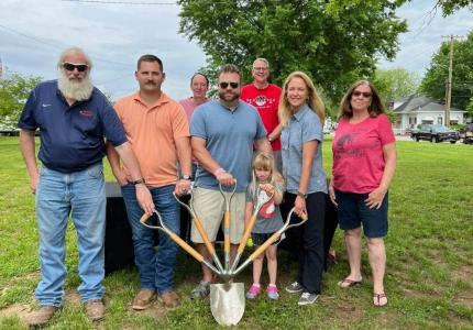 Photo of individuals posing for a ground breaking in a park