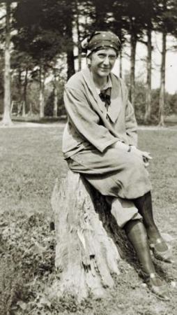Photographer Clara Weisheit sitting on a stump around 1925